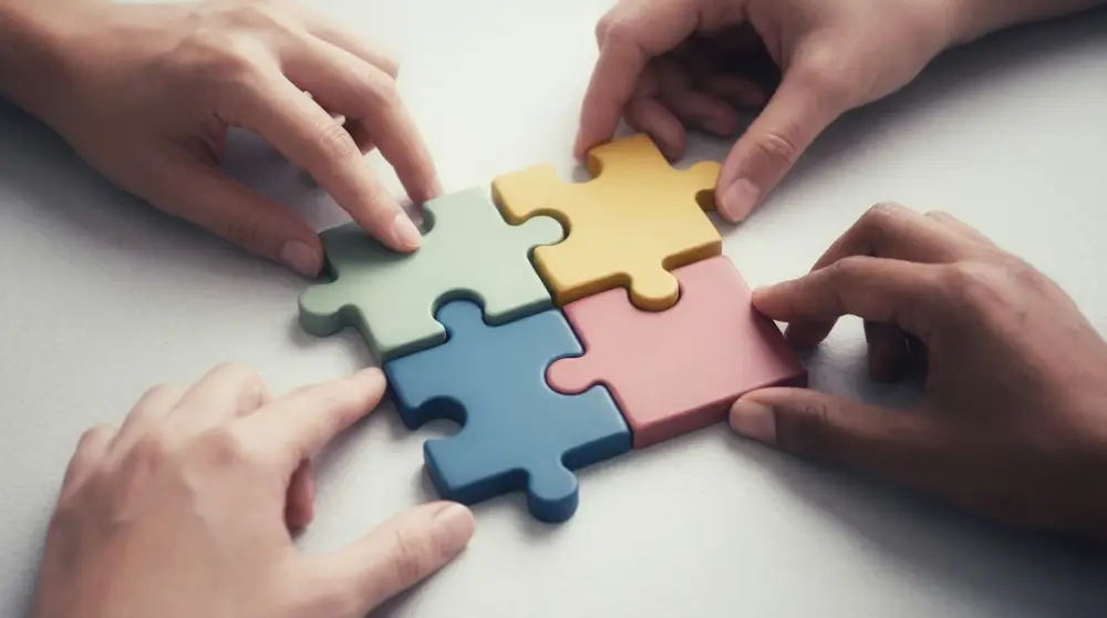 Hands connecting colorful puzzle pieces together, illustrating connecting leadership priorities with practical plans